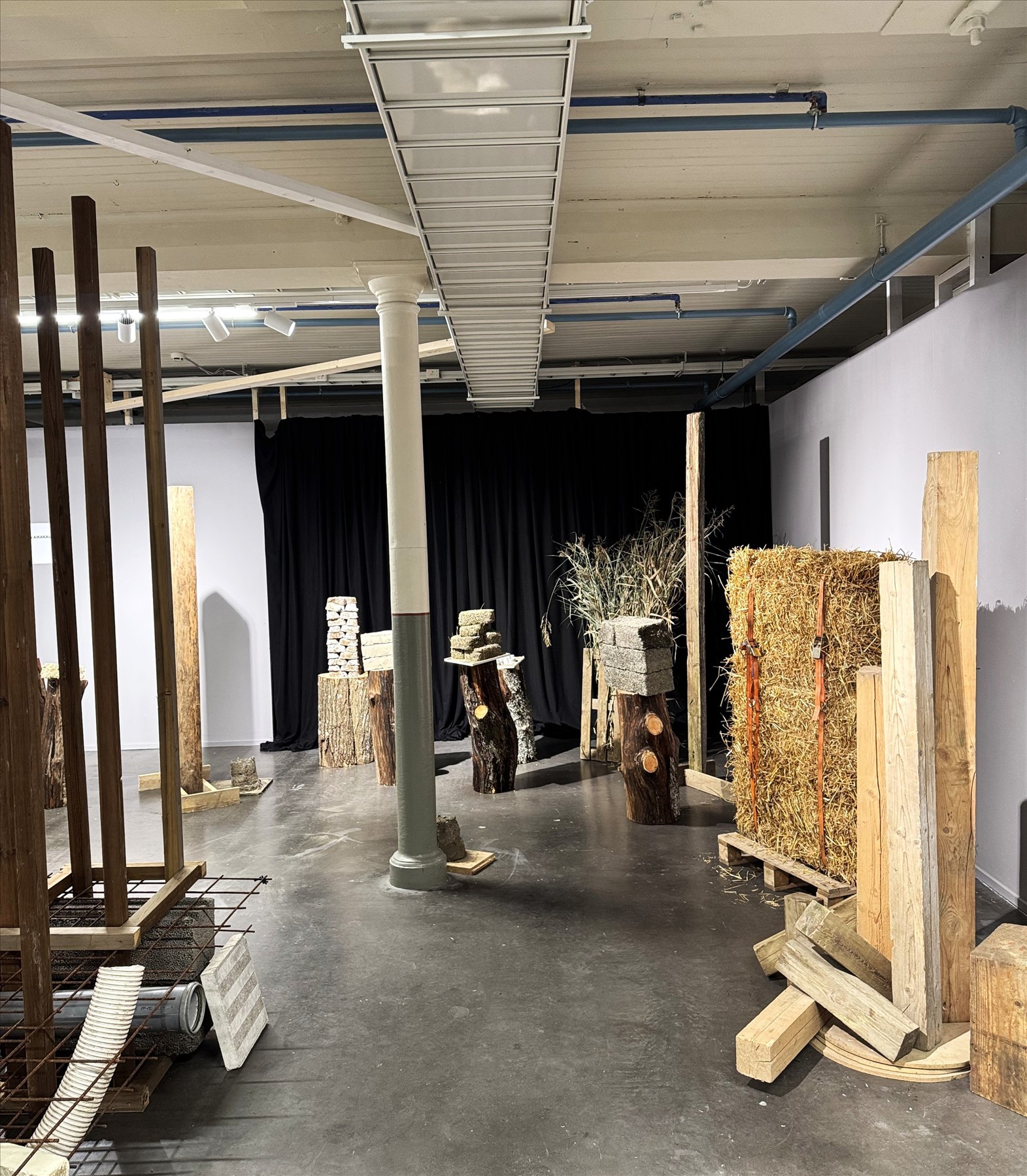 Exhibition installation view with timber, straw, and material samples